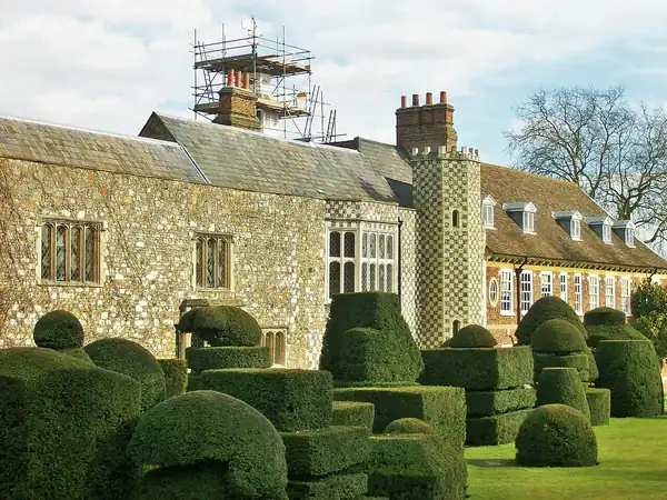 Clipped topiary in the gardens in front of the flint and chequerwork walls of Hall Place, Bexley