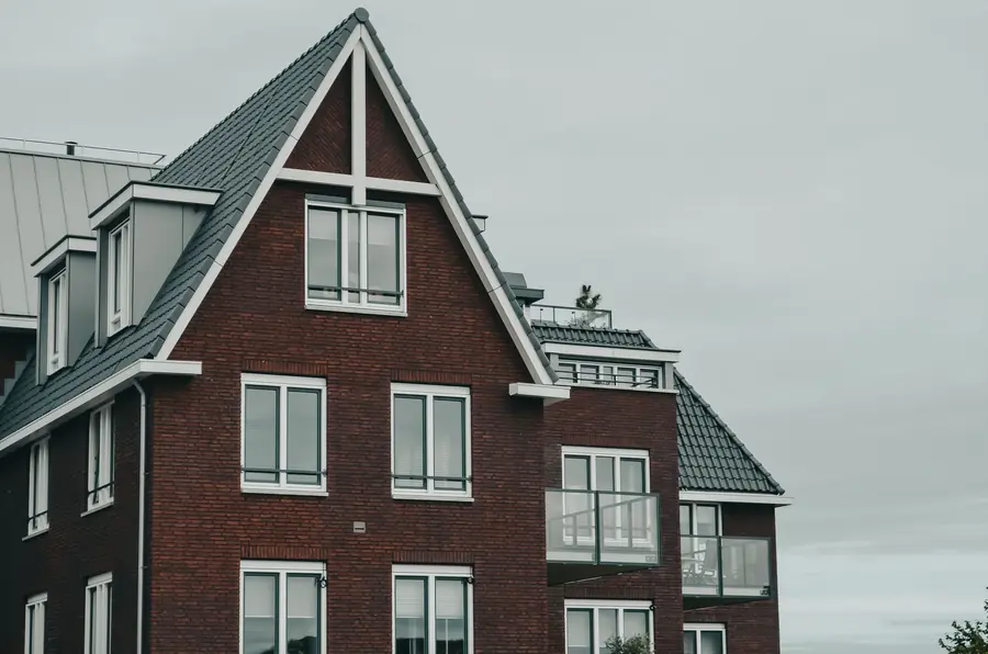 Brick new-build with a steep tiled gable and white dry verge trim, where dry-fix verge caps can loosen after ten years