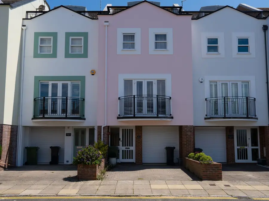 Row of rendered new-build townhouses with small gables and roof abutments between neighbouring homes, typical of 2000s estates