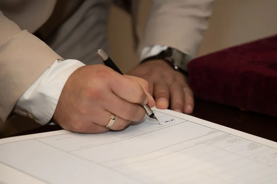 Hand signing a detailed written roofing quote at a table, the paperwork every Dartford homeowner should get before work starts