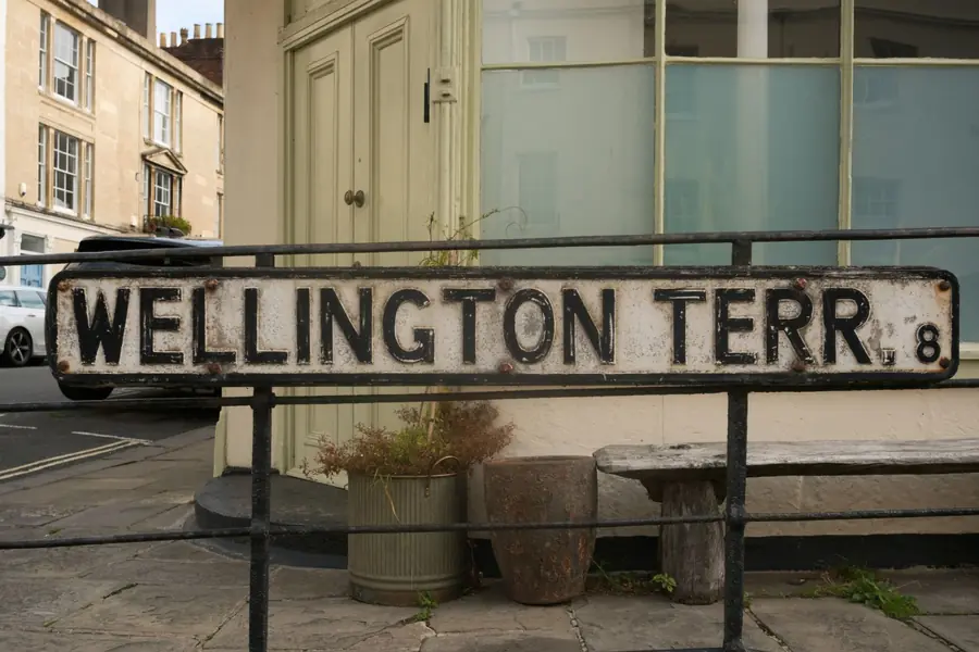 Old cast iron terrace street sign on railings, a reminder that re-roofing a terraced house means dealing with the party wall