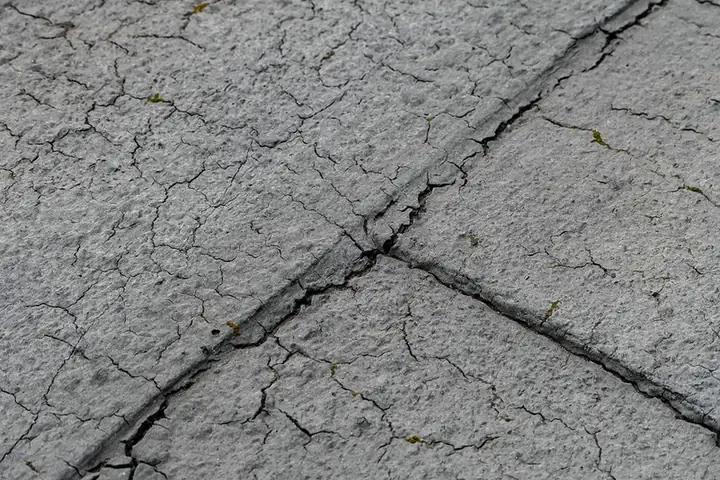 Close-up of an ageing bitumen felt flat roof with the surface crazed and the lap joints splitting open