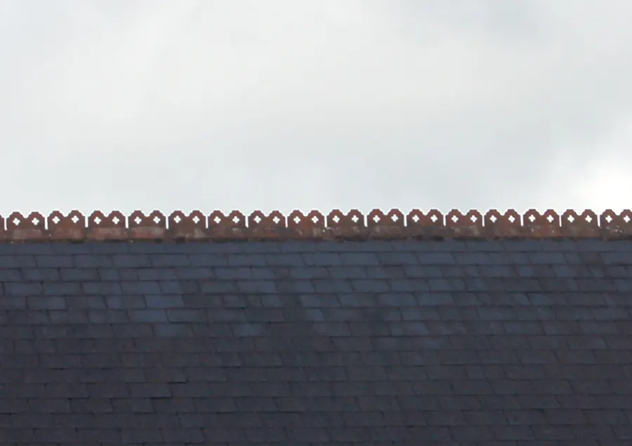 Slate roof finished with a row of decorative crested clay ridge tiles along the ridge line