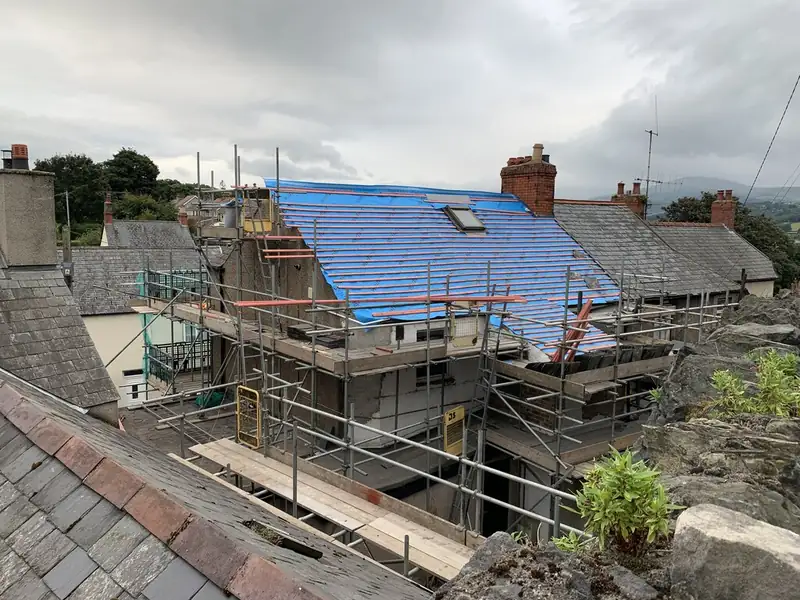 Terraced house roof stripped back to blue breathable membrane and new battens, with scaffolding along the front