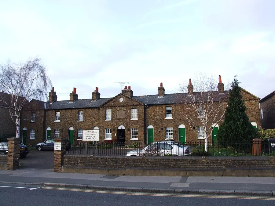 Gartly Cottages, a long row of 19th-century brick almshouse cottages with chimney stacks in Dartford